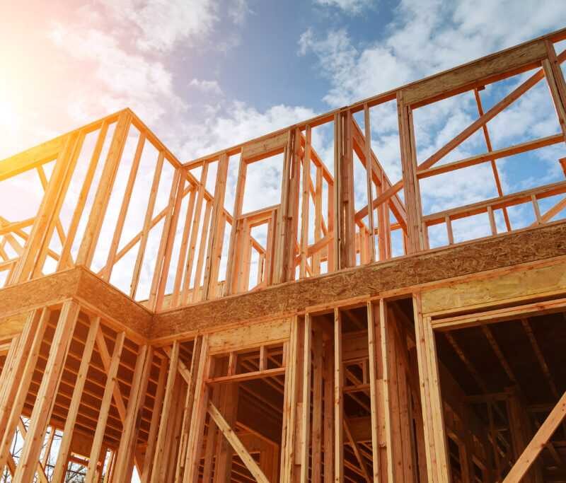 New residential construction loans home framing against a blue sky. Roofing construction. Wooden construction HFG Trust