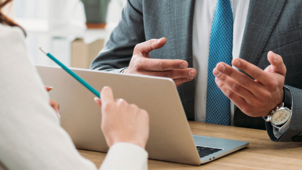 Initial meeting with a fiduciary financial advisor, client taking notes on a laptop during planning