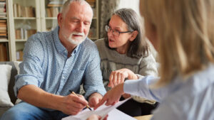 Older couple reviewing and signing power of attorney documents with an advisor at home
